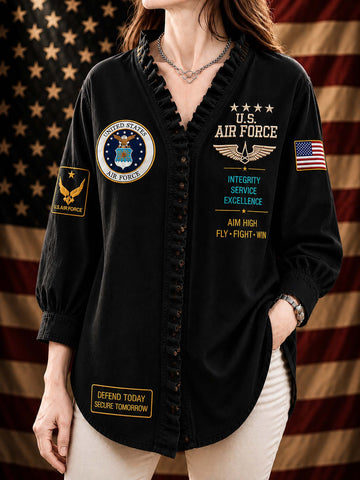 A woman wearing a black long-sleeve button-front shirt with ruffled trim, military-inspired patches, and U.S.