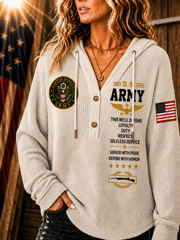 A woman wearing a light beige waffle-knit hoodie sweatshirt with military-themed graphics, including 'U.S.