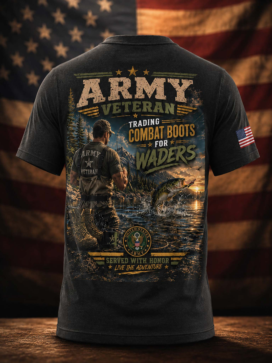 A dark charcoal gray t-shirt shown from the back, featuring a large graphic print with a military fishing scene, a fish jumping out of the water, and text reading 'ARMY VETERAN' and 'TRADING COMBAT BOOTS FOR WADERS'. The t-shirt is displayed against a blurred American flag background on a wooden surface.