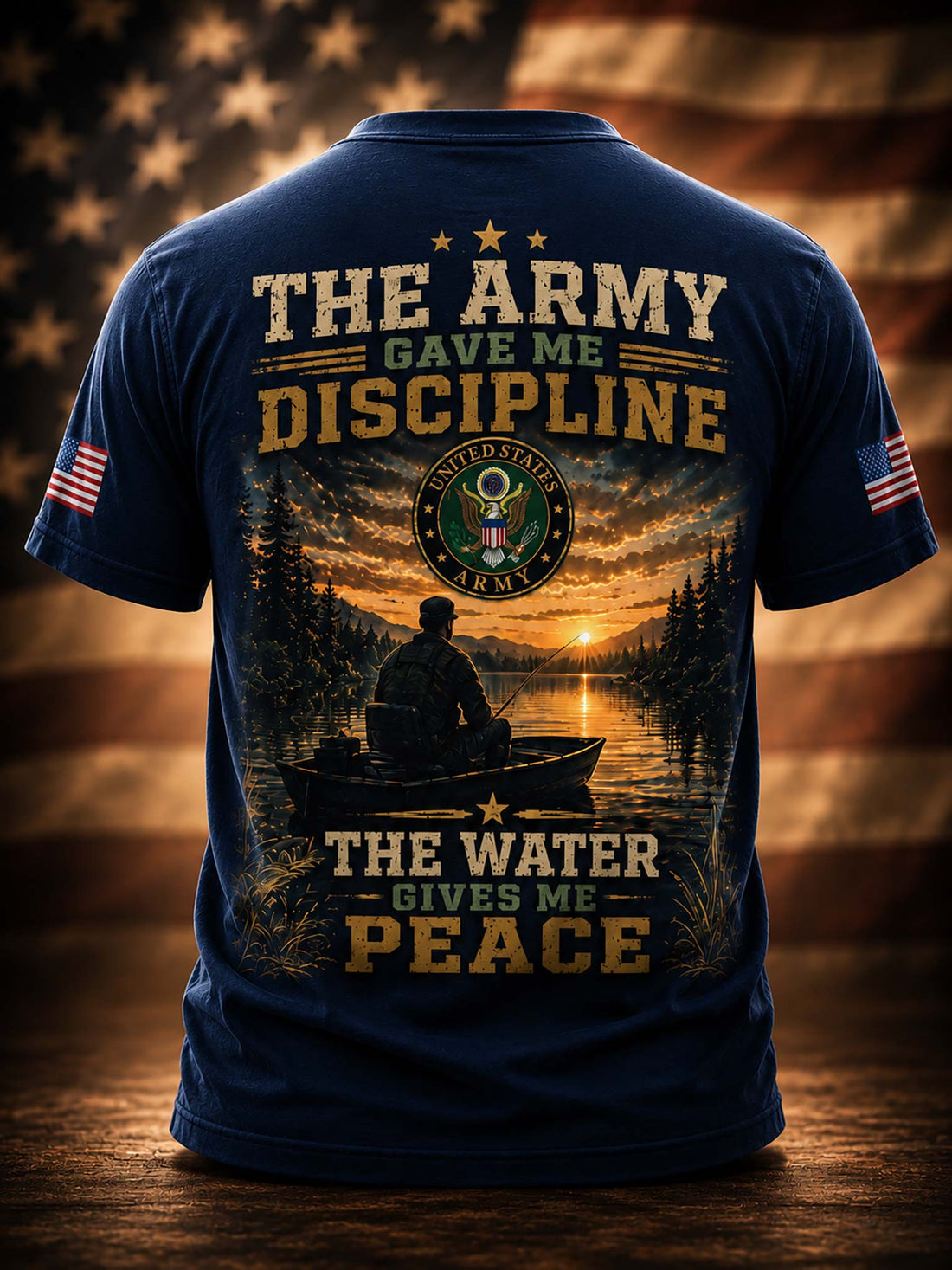 A black graphic t-shirt shown from the back, featuring military-themed text, a sunset over water with a silhouetted figure in a boat, a circular emblem, and American flag patches on the sleeves. The shirt is centered against a dramatic, warm-toned blurred background.
