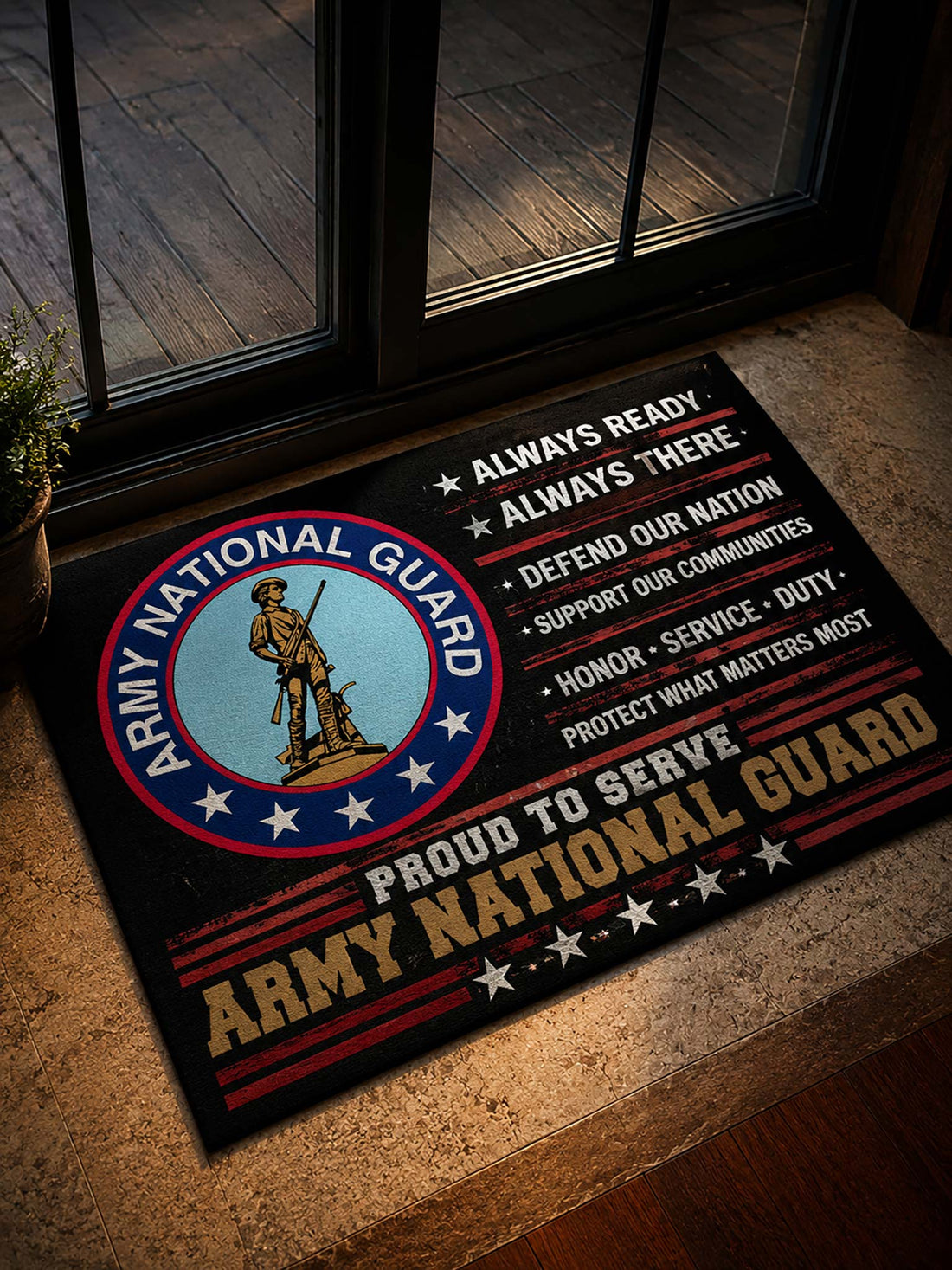 A rectangular Army National Guard doormat placed on a stone entryway floor in front of glass doors. The mat has a black background with the Army National Guard seal on the left, white and gold text reading 'Always Ready,' 'Always There,' 'Proud to Serve,' and 'Army National Guard,' plus red and white stars and stripes accents.