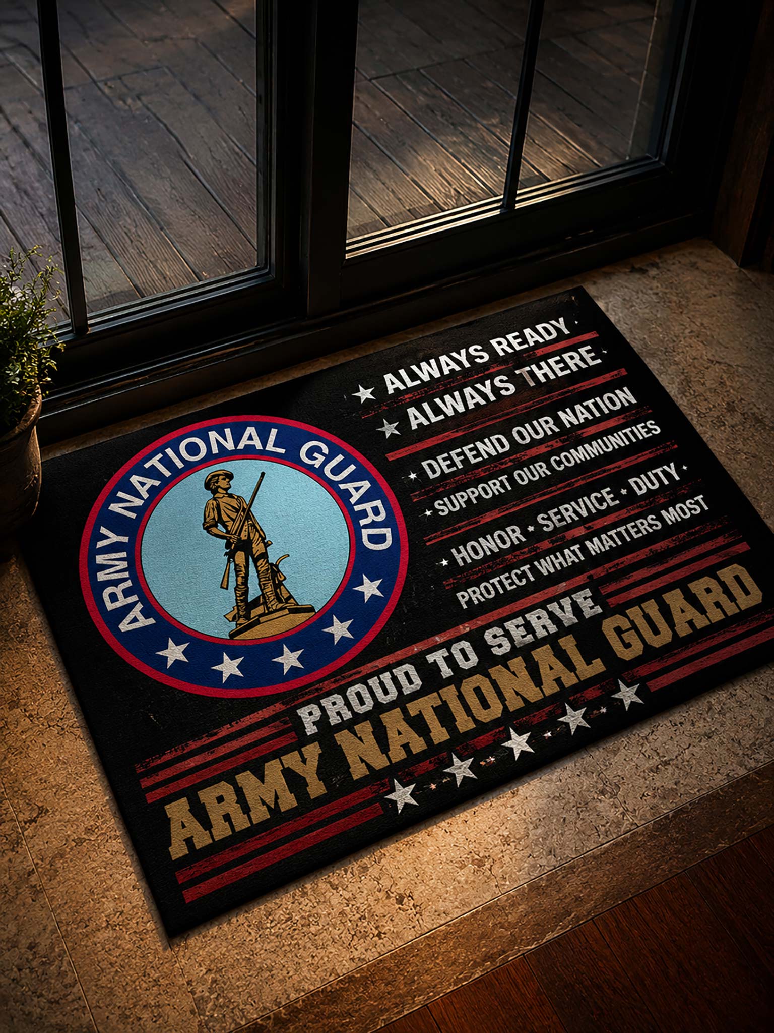 A rectangular Army National Guard doormat placed on a stone entryway floor in front of glass doors. The mat has a black background with the Army National Guard seal on the left, white and gold text reading 'Always Ready,' 'Always There,' 'Proud to Serve,' and 'Army National Guard,' plus red and white stars and stripes accents.
