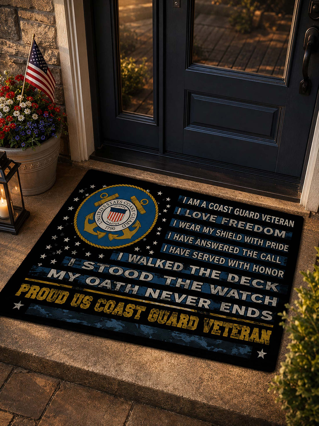 A rectangular doormat with a Coast Guard-themed design, placed on a stone entryway floor in front of glass doors. The mat features a large blue and gold Coast Guard emblem, white and yellow text reading patriotic service quotes, and a dark navy background with white stars.