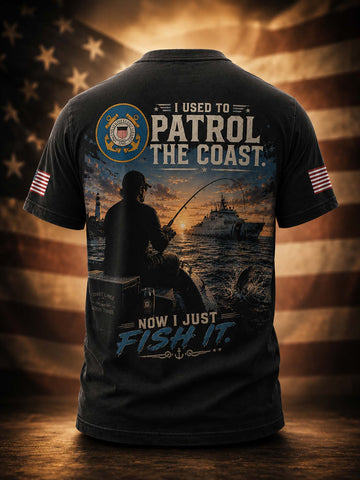 A black short-sleeve t-shirt shown from the back, featuring a large patriotic fishing graphic with a sailor, a boat, and the text 'I USED TO PATROL THE COAST. NOW I JUST FISH IT.