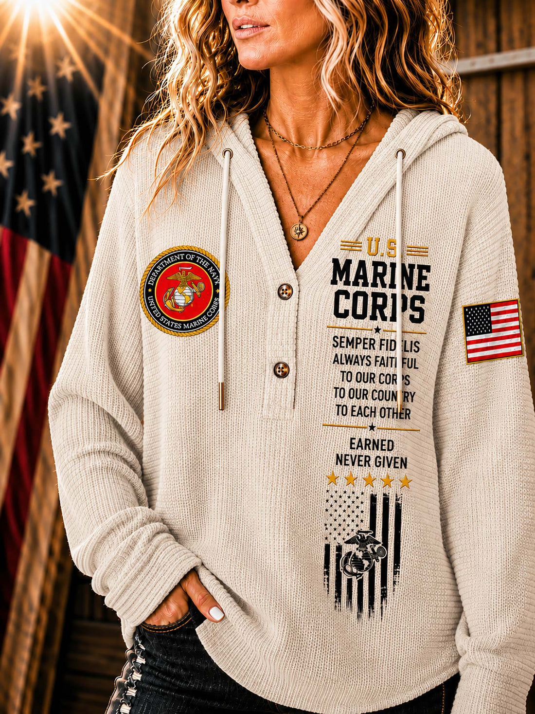 A woman wearing a beige waffle-knit hoodie with military-themed graphics, including a U.S.