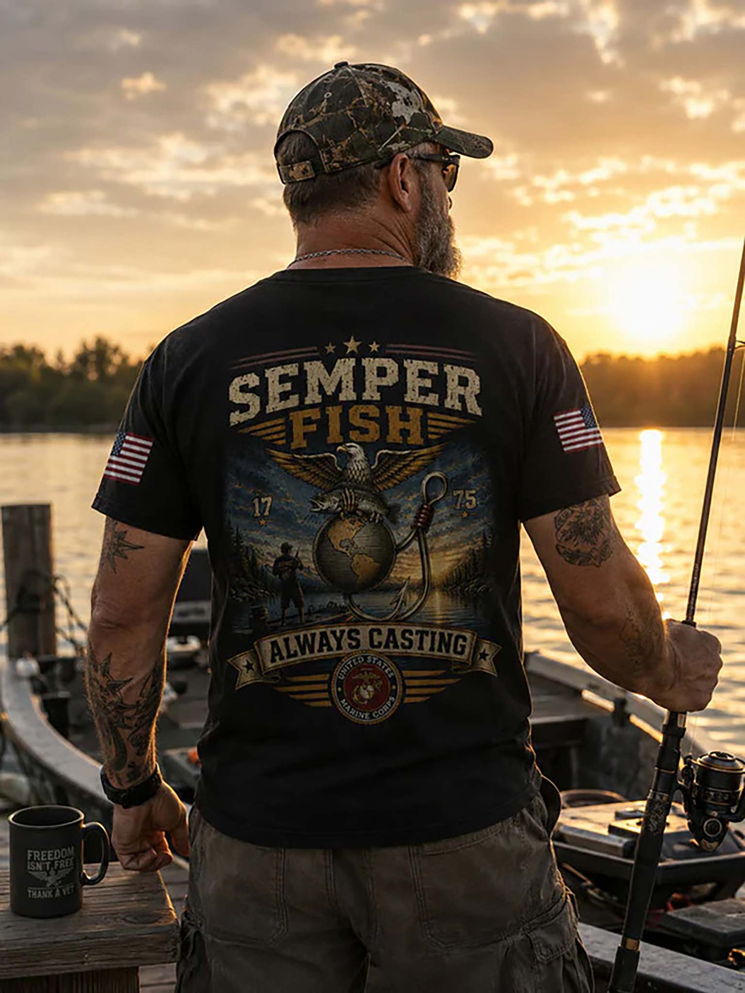 A man stands on a dock at sunset wearing a black graphic t-shirt with 'SEMPER FISH' and 'ALWAYS CASTING' printed on the back, along with a camouflage cap and holding a fishing rod.