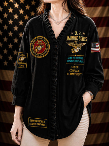 A woman wearing a black long-sleeve button-front shirt with military-themed patches and text, including U.S.