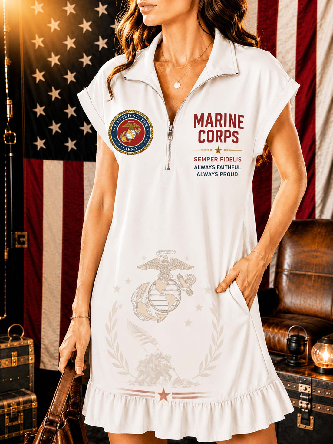 A woman models a white short-sleeve polo dress with a half-zip neckline, featuring 'MARINE CORPS' text, a Marine Corps emblem, and a large Marine Corps eagle, globe, and anchor insignia printed on the front. The background features a rustic American flag, leather furniture, and vintage suitcases.