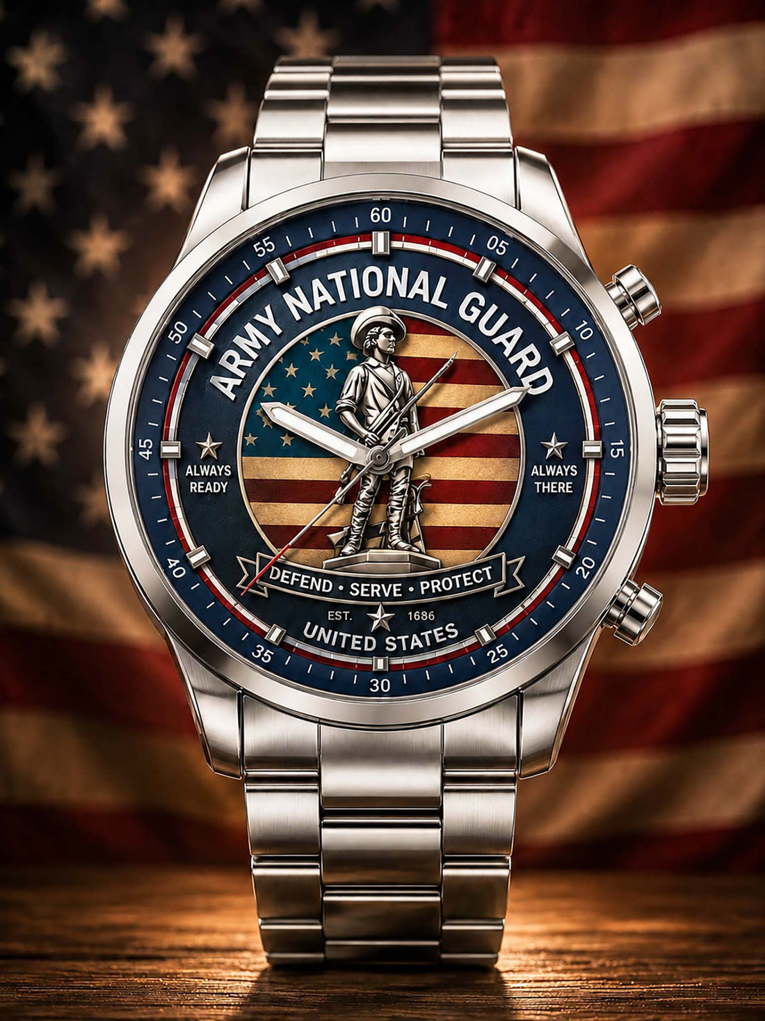 A stainless steel military-themed watch with a round silver-tone case and link bracelet, featuring a detailed dial with the words 'ARMY NATIONAL GUARD,' an American flag background, a central soldier statue, and text including 'DEFEND • SERVE • PROTECT' and 'UNITED STATES.' The watch is photographed on a wooden surface with a blurred American flag backdrop.
