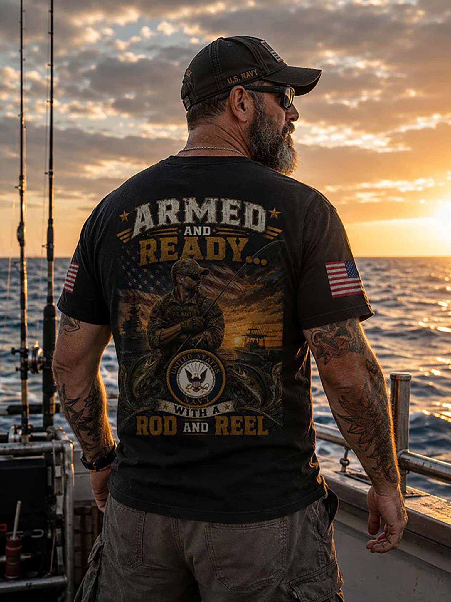 A man stands on a boat at sunset wearing a black graphic T-shirt with a large patriotic fishing design on the back, reading 'ARMED AND READY.