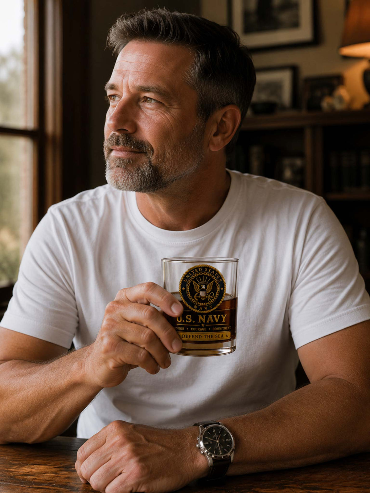 A man in a white crewneck t-shirt holding a clear glass tumbler with a U.S.