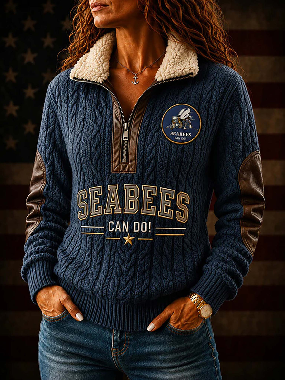 A woman wearing a navy blue cable-knit quarter-zip sweater with a cream sherpa collar, brown faux-leather sleeves, and 'SEABEES CAN DO!' printed on the front, posed against a dark American flag background.