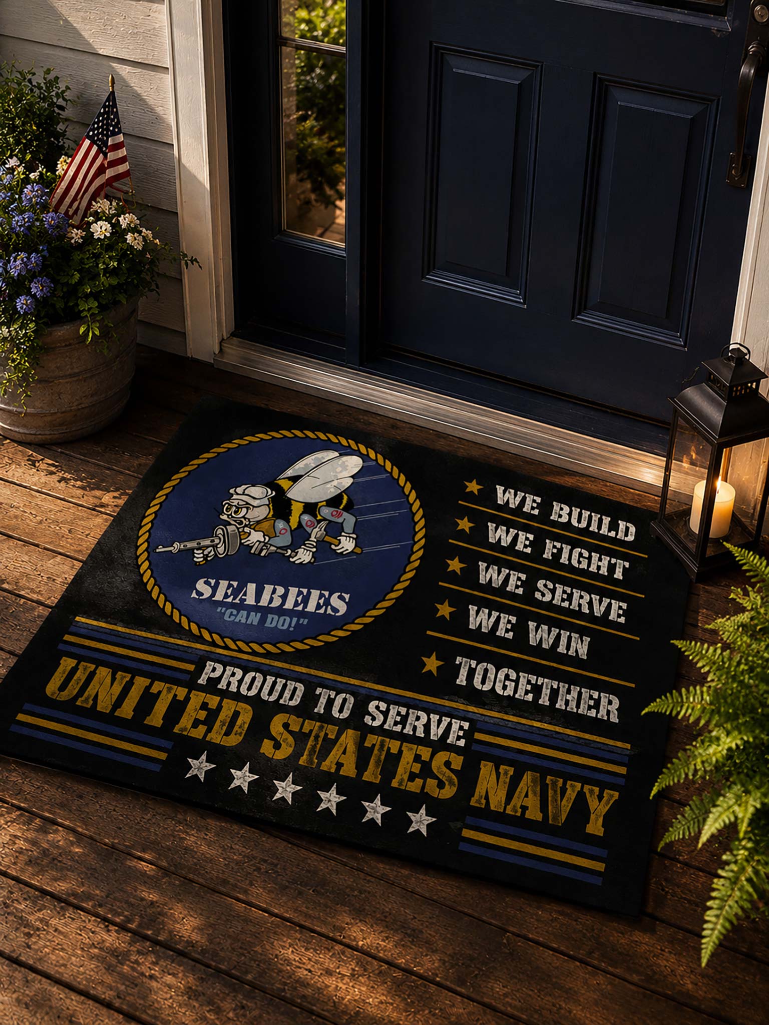 A United States Navy Seabees doormat displayed on a wooden porch in front of a dark blue door. The mat features a navy blue background with gold and white text, a circular emblem of Seabees with a robot and tools, and the phrases 'PROUD TO SERVE UNITED STATES NAVY' and 'WE BUILD WE FIGHT WE SERVE WE WIN TOGETHER'.