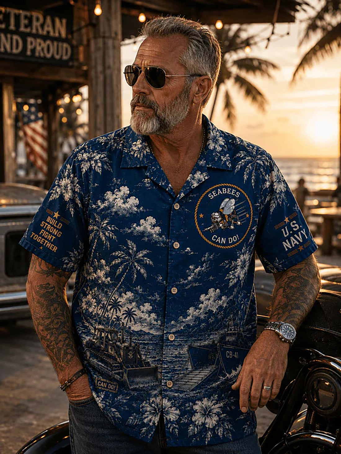 A short-sleeve button-up camp shirt in navy blue with a white tropical floral and nautical print, laid flat on a dark wood surface. The shirt features U.