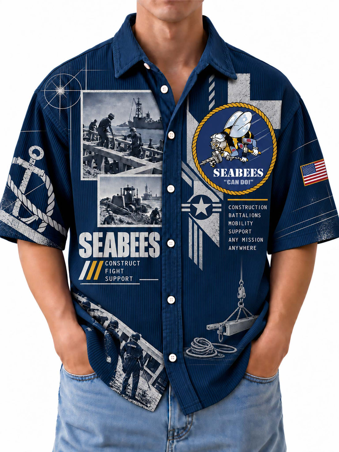 A man wearing a navy blue short-sleeve button-up shirt with a detailed US Navy Seabees graphic print, paired with light blue jeans against a white background.