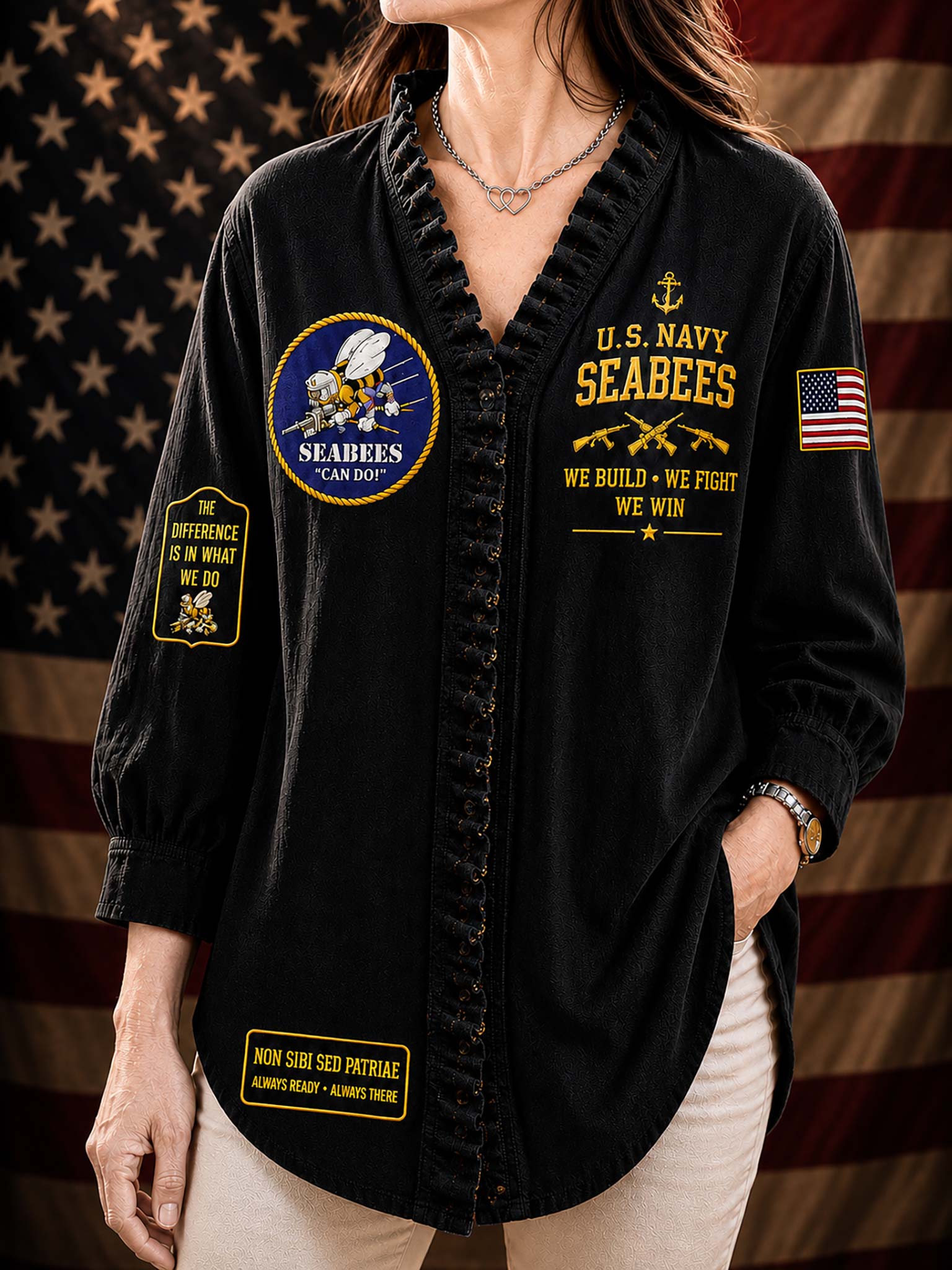 A woman wearing a black long-sleeve button-front shirt with ruffled trim, featuring gold and multicolor U.S.