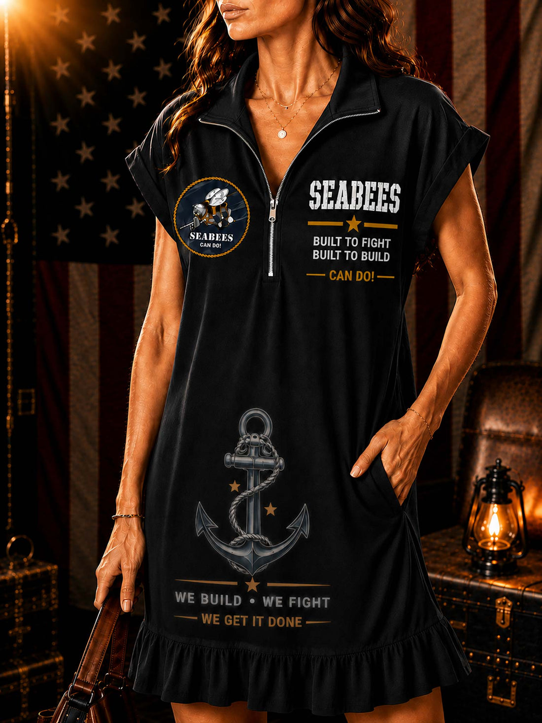 A woman models a white short-sleeve polo dress with a ruffled hem, featuring 'SEABEES' text, an anchor graphic, and a circular patch on the front. The background features an American flag, a leather trunk, and a lantern.