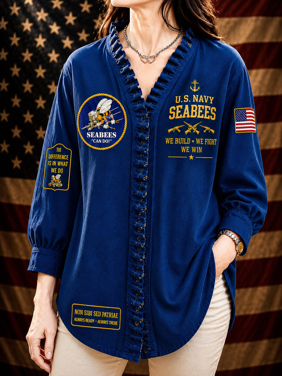 A woman wearing a black long-sleeve button-front shirt with ruffled trim, featuring gold and multicolor U.S.