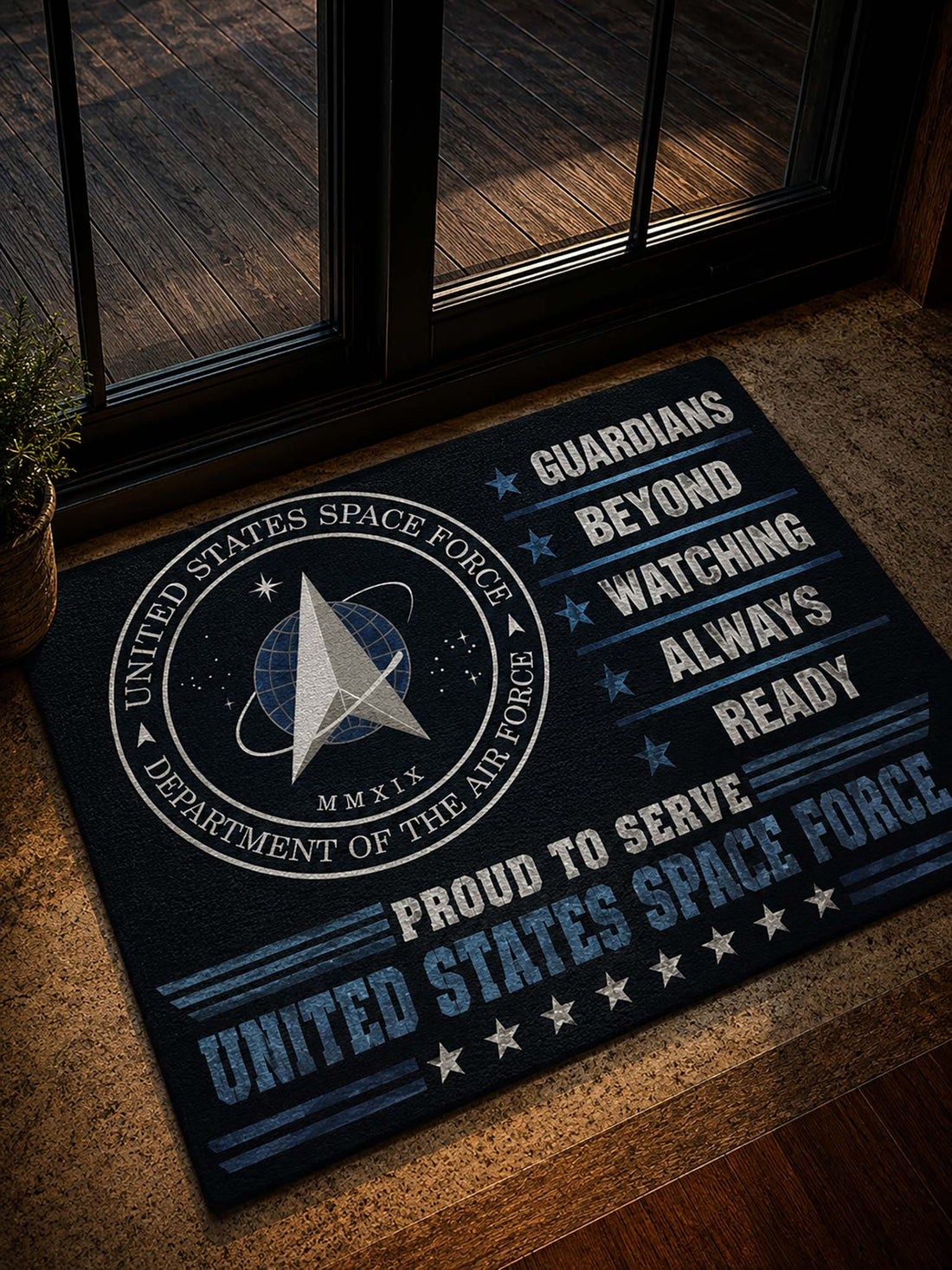 A rectangular doormat with a United States Space Force design, placed on a tan stone or concrete step in front of glass doors. The mat is dark navy with white and light blue text and graphics, including the Space Force emblem and the words 'Guardians Beyond Watching Always Ready' and 'Proud to Serve United States Space Force.