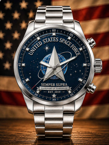 A stainless steel wristwatch with a dark blue space-themed dial featuring the United States Space Force emblem and text, shown against a blurred American flag and wooden surface background.