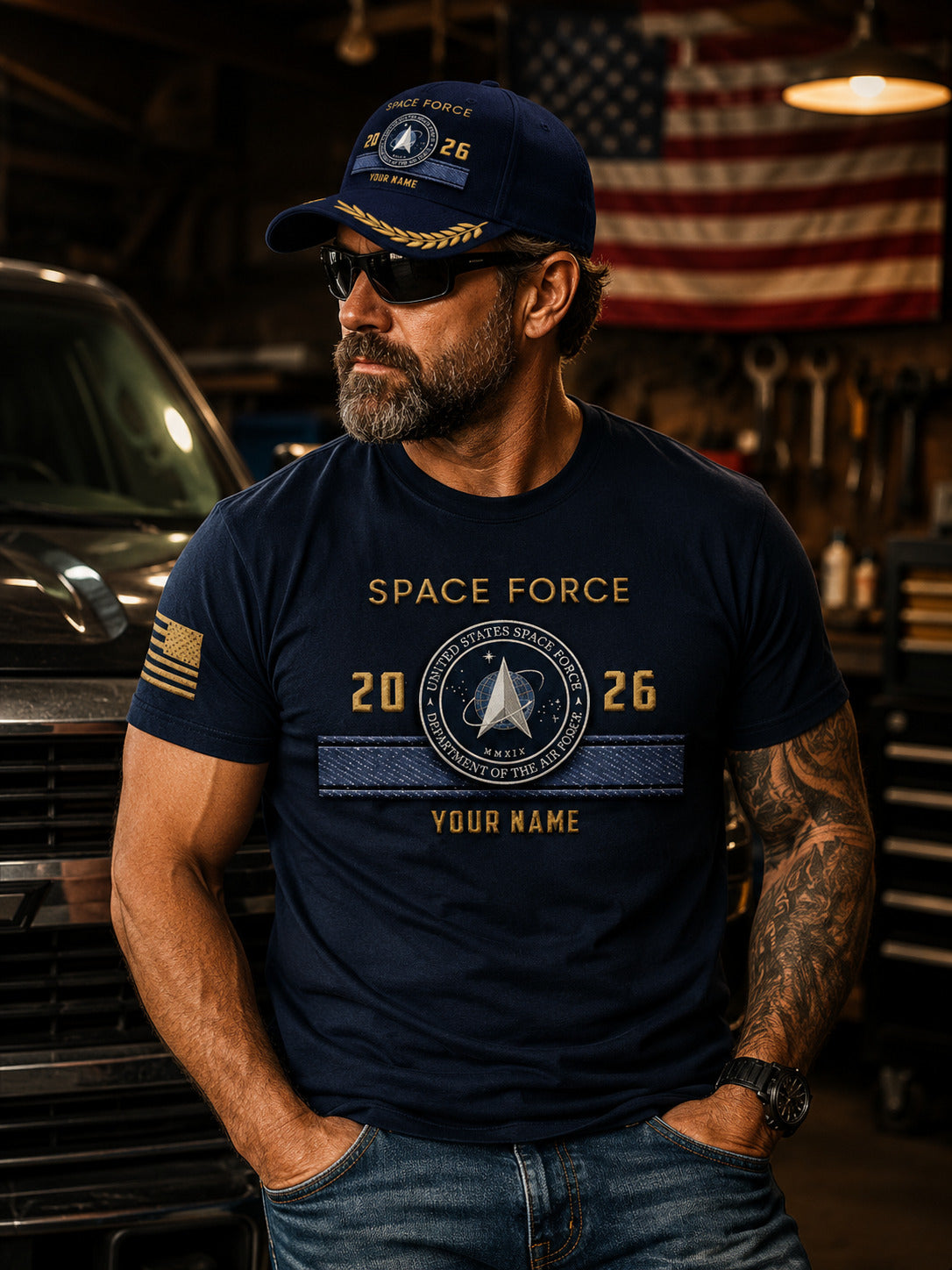 A navy blue baseball cap with gold embroidered details, featuring a 'Space Force' emblem on the front, displayed on a wooden surface with a blurred American flag in the background.