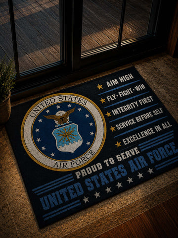 A rectangular doormat with a United States Air Force emblem and slogan text, placed on a wooden floor in front of glass doors.