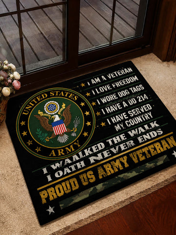 A rectangular black doormat with a large United States Army emblem and patriotic text, placed on a beige carpet in front of a glass door.