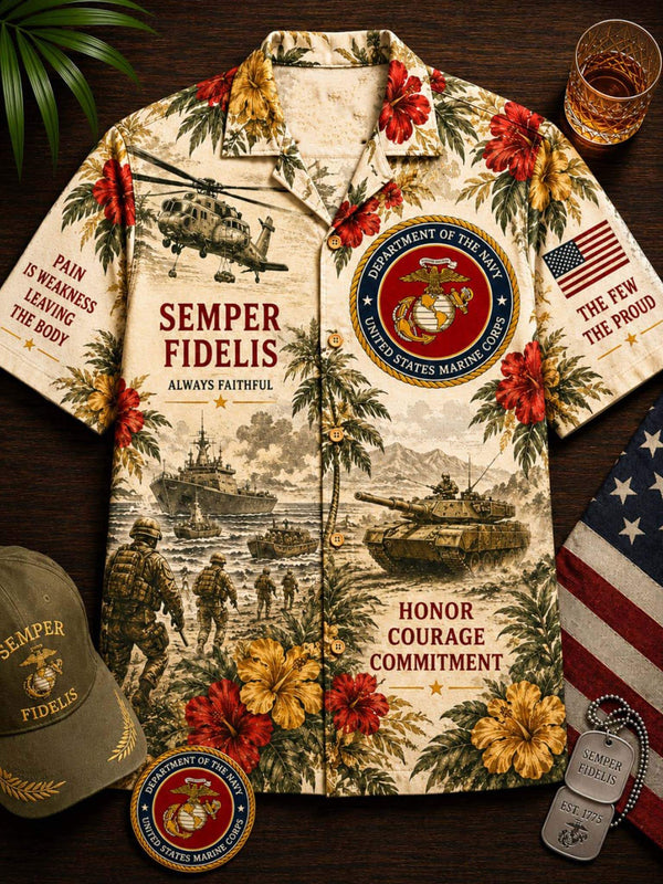 A short-sleeve button-up camp shirt laid flat on a dark wood surface, printed with tropical flowers, military scenes, and U.S.