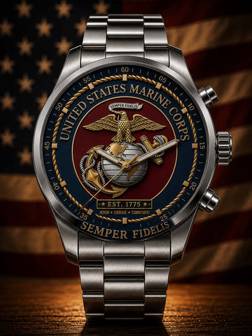 A stainless steel military-style wristwatch with a United States Marine Corps themed dial, featuring the Eagle, Globe, and Anchor emblem, gold lettering, and a dark red center, set against a blurred American flag background.