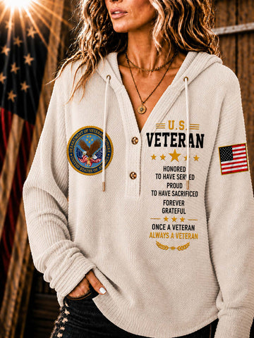 A woman wearing a cream-colored V-neck pullover hoodie with a 'U.S.