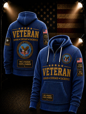 A blue pullover hoodie shown from both front and back, featuring large gold 'VETERAN' text, smaller white text, an eagle emblem, American flag patches, and drawstring hood. The hoodie is displayed against a dark patriotic background with spotlights and an American flag.