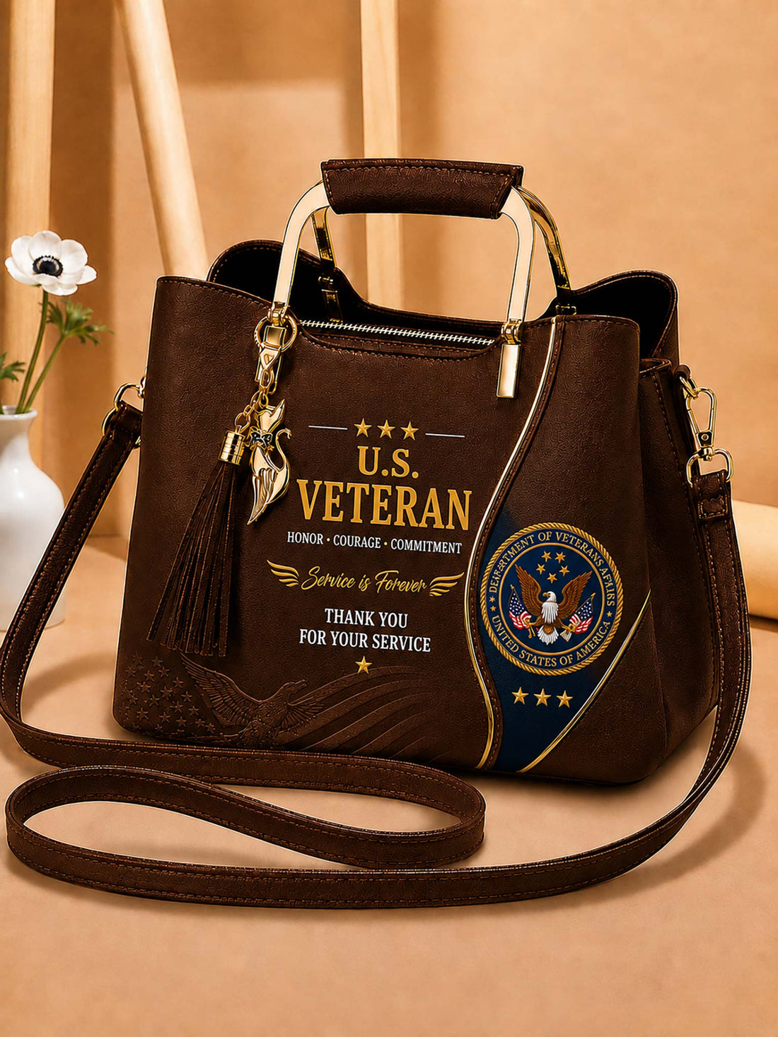 A dark brown faux-leather handbag with a top handle and shoulder strap, decorated with a gold and blue U.S.