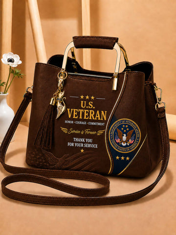 A dark brown faux-leather handbag with a top handle and shoulder strap, decorated with a gold and blue U.S.