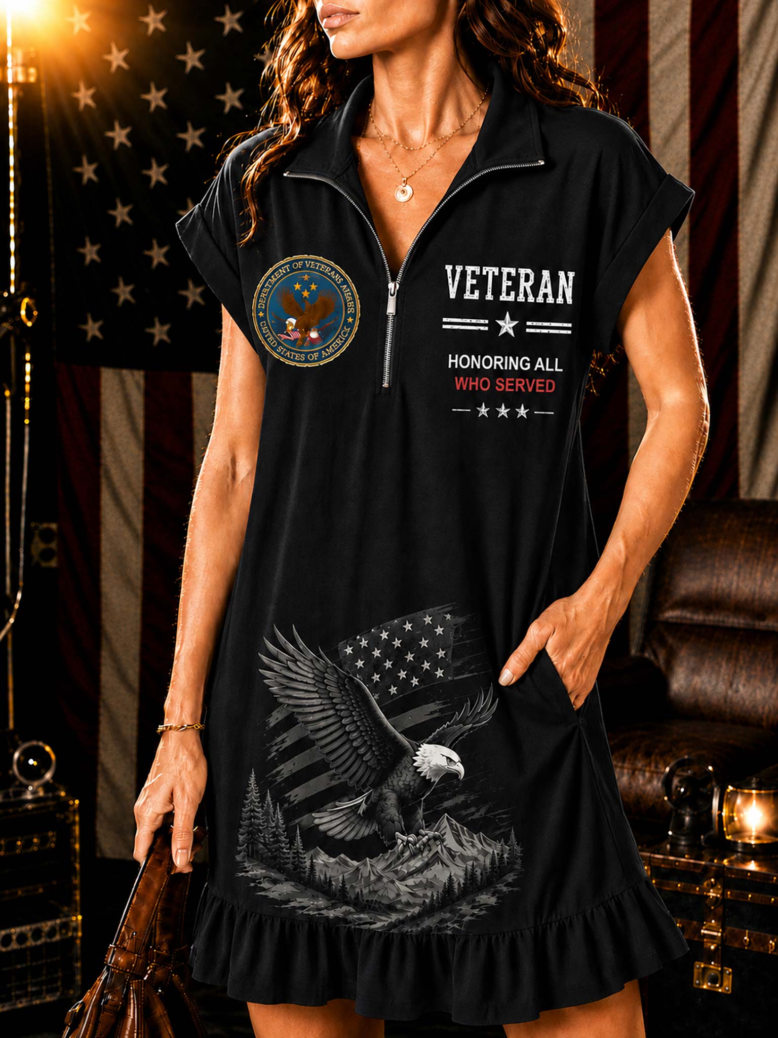 A woman wearing a black short-sleeve mini dress with a half-zip collar, featuring a military-style patch on the left chest, white and red 'VETERAN HONORING ALL WHO SERVED' text on the right chest, and a large eagle graphic with an American flag on the front.