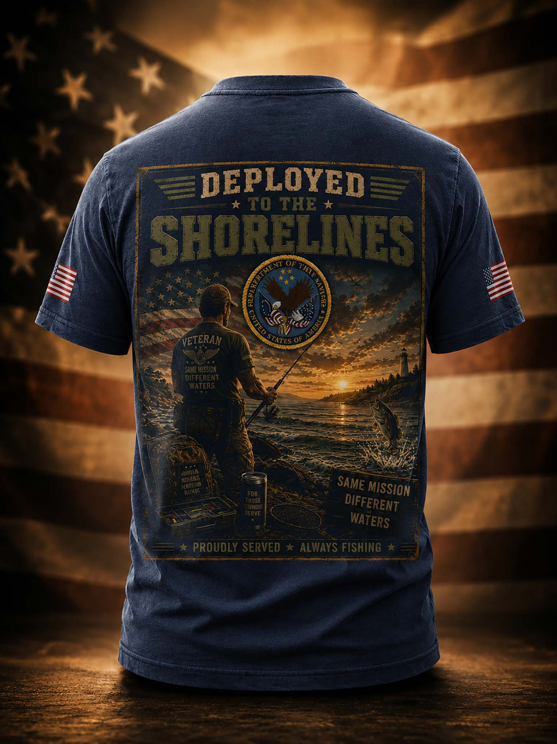 A black short-sleeve t-shirt shown from the back, featuring a large graphic print with a military fishing scene, the text 'DEPLOYED TO THE SHORELINES,' and a circular emblem. The shirt is displayed against a warm, blurred American flag background with a wooden surface below.