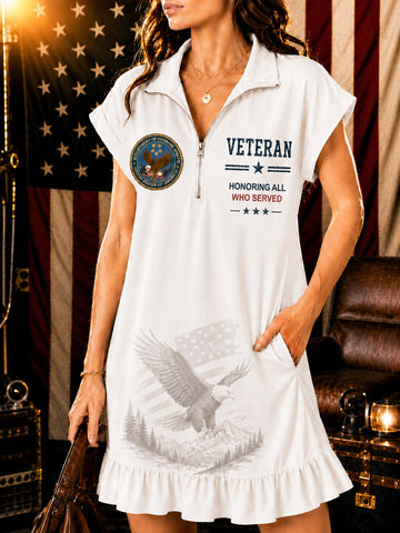 A woman wearing a white short-sleeve polo shirt dress with a front zipper, 'VETERAN' text, a circular patch graphic, and a gray eagle print on the front, posed in front of an American flag and leather furniture.