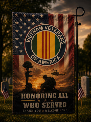 A vertical garden flag on a black metal stand, featuring the Vietnam Veterans of America emblem over an American flag and military memorial scene at sunset, with the text 'Honoring All Who Served' and 'Thank You Welcome Home.'.
