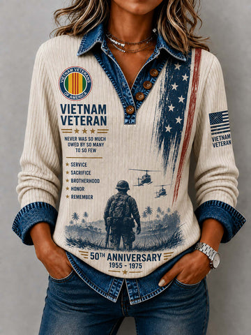 A woman wearing a cream ribbed long-sleeve shirt with a denim collar and cuffs, decorated with a detailed Vietnam Veteran 50th Anniversary graphic print, paired with blue jeans.