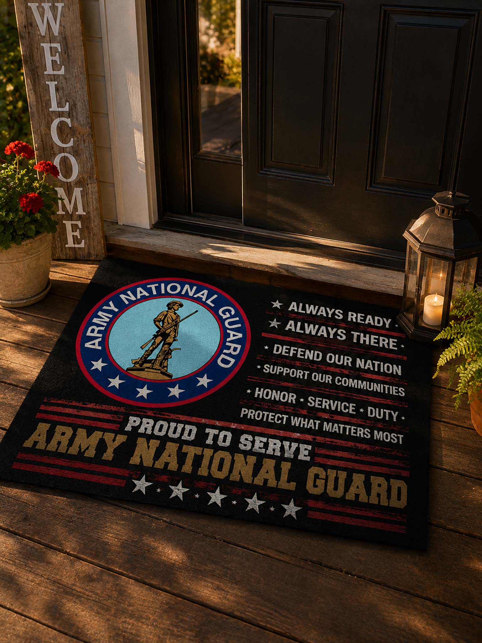 A rectangular Army National Guard doormat placed on a wooden porch in front of a dark door. The mat features the Army National Guard emblem on the left, white text reading 'Always Ready, Always There, Defend Our Nation, Support Our Communities, Honor Service Duty, Protect What Matters Most,' and large 'Army National Guard' text at the bottom.