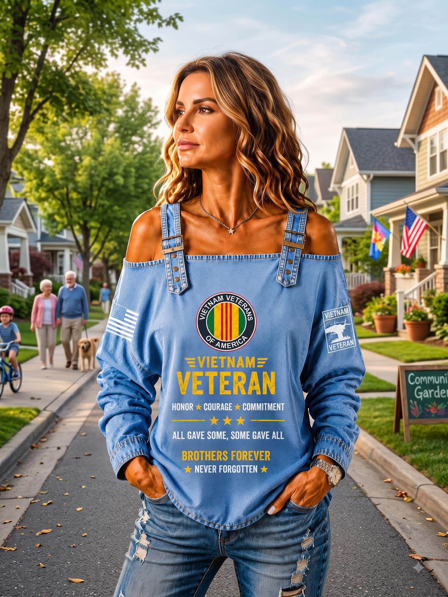 A woman stands on a suburban street wearing a light blue off-the-shoulder long-sleeve shirt with a large Vietnam Veterans American emblem and text on the front, paired with distressed blue jeans.