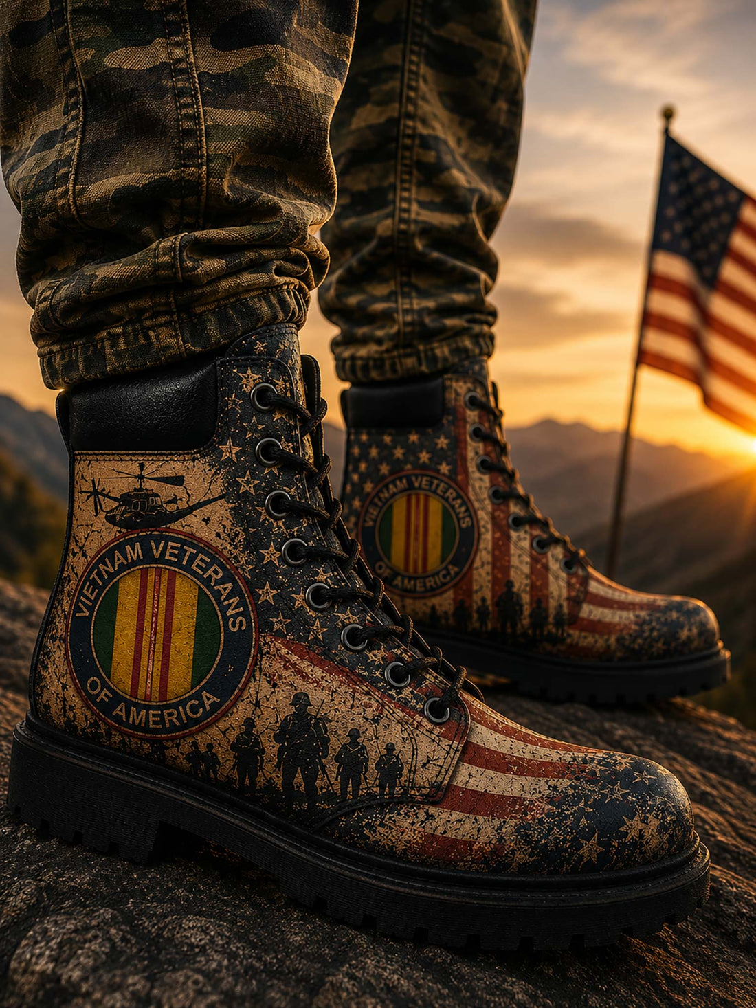 A pair of distressed military-style boots with a patriotic American flag and stars-and-stripes print, displayed inside a cardboard box with a hand holding one boot. The boots feature circular 'Vietnam Veterans of America' emblems and a helicopter graphic.