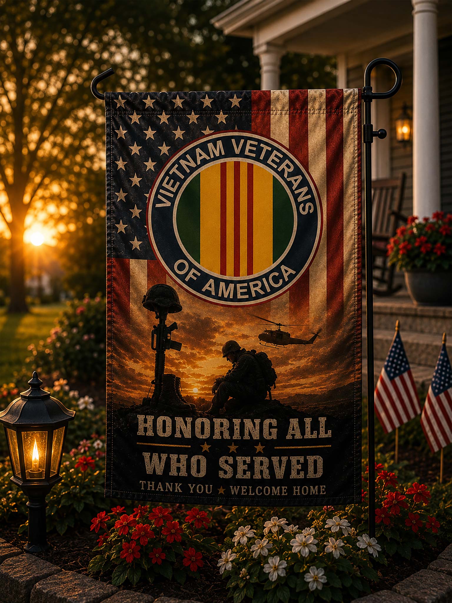 A vertical garden flag displayed on a black metal stand in a front yard at sunset. The flag features a distressed American flag background, a circular 'Vietnam Veterans of America' emblem, soldier silhouettes, and the text 'Honoring All Who Served' and 'Thank You Welcome Home.